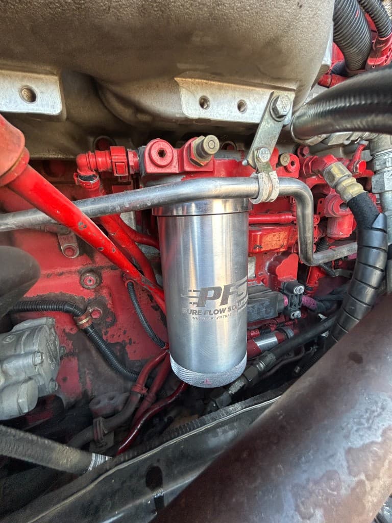 PurePower lifetime filter with Pure Flow Solutions branding installed on a Cummins ISX 15 engine